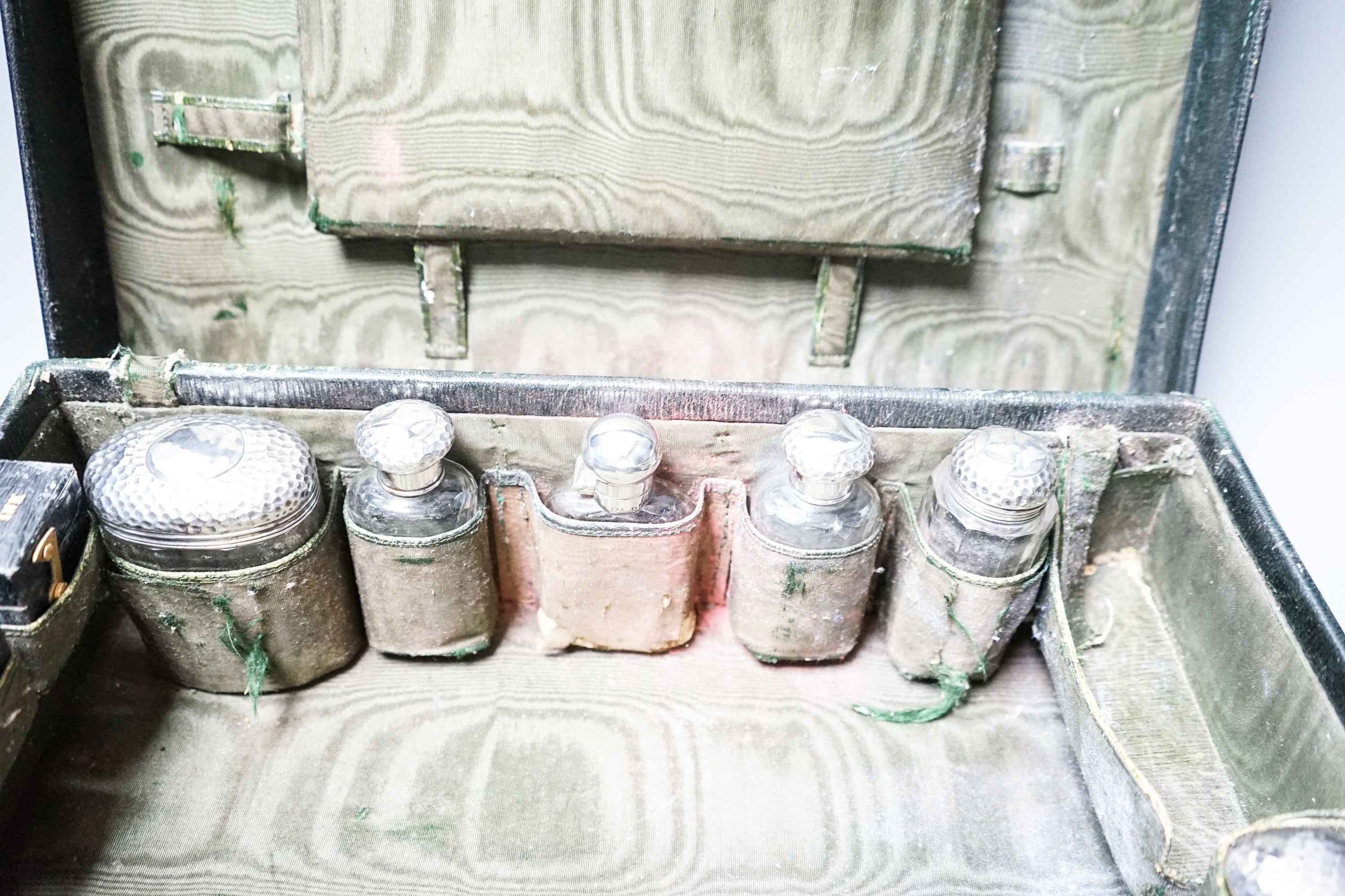 An Edwardian Harrod's traveling toilet case, fitted with six silver mounted toilet accessories, including an associated hip flask, case 40.3cm.